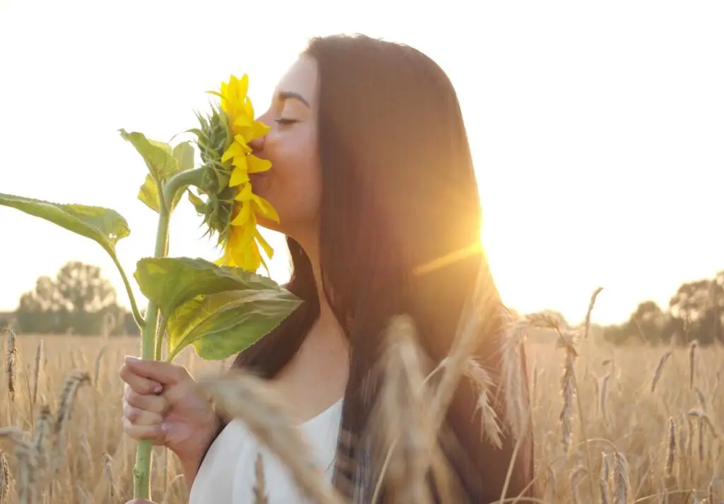 Woman in a field smelling a sunflower