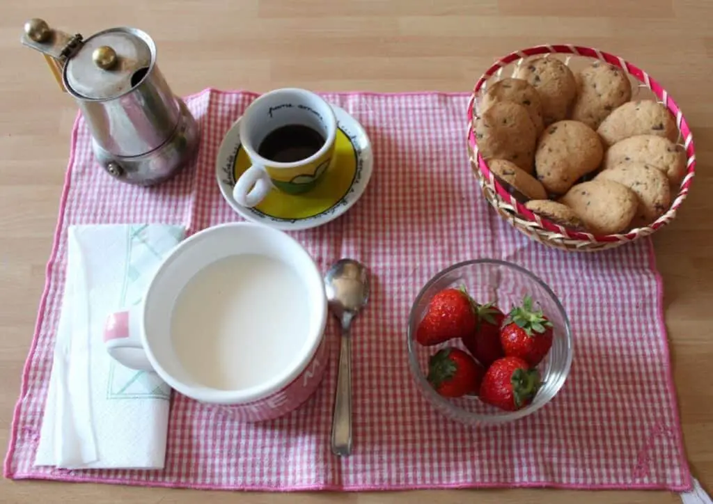 Italian breakfast with espresso, cookies, milk and strawberries